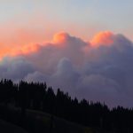 a sunset view of some clouds and trees