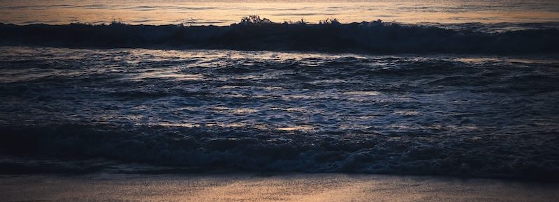 the sun is setting over the ocean on the beach