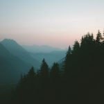 a view of a mountain range with trees in the foreground