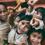 five children smiling while doing peace hand sign